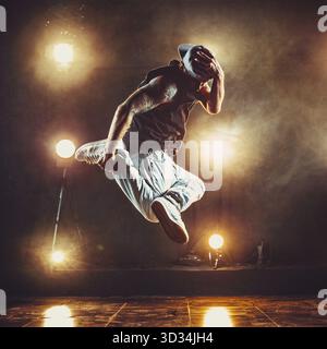 Young cool man break dancer jumping in club with lights and smoke. Tattoo on body Stock Photo