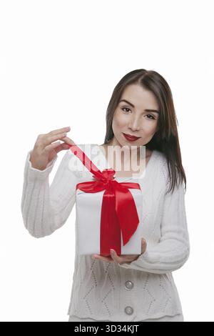 Happy young woman with birthday present in hands posing in studio Stock Photo