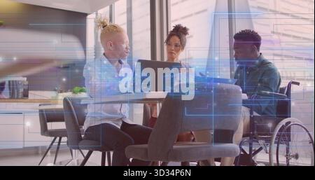 Collaborating wheelchair user and two colleagues using laptop in kitchen with digital overlays Stock Photo