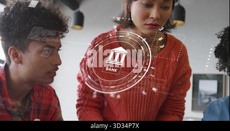 Collaborating Asian woman in red sweater leaning at table in office, exploring banking hologram Stock Photo