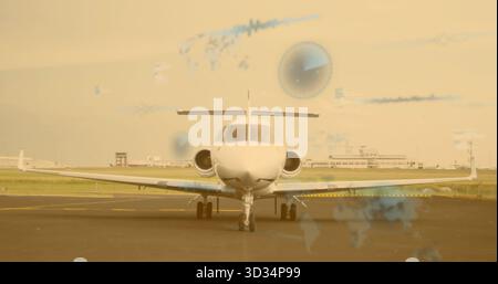 Parking private jet on runway with yellow stripe, terminals and tower, overlaid world-map charts Stock Photo