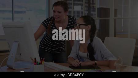 Collaborating two women using stylus on graphics tablet at desk in office, with color swatches Stock Photo