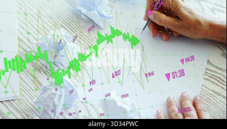 Sketching notes with ballpoint pen on paper sheets at wood desk, with digital candlestick chart Stock Photo