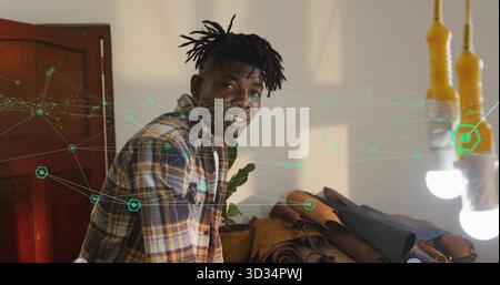 Leaning craftsman wearing plaid shirt arranging leather hides in studio, with hanging bulbs Stock Photo