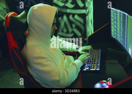 Hacker in hoodie working hacks code site on personal computer laptop Stock Photo