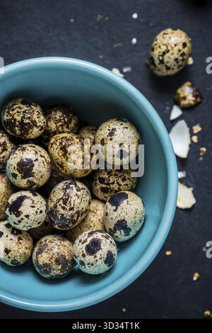 Quail eggs in pastel bowl on dark background, Easter decoration concept. View from overhead Stock Photo