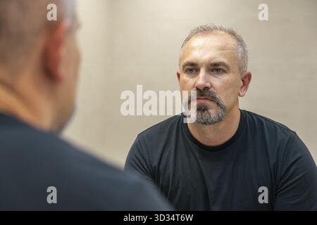 Middle-aged handsome man looking in mirror in a bathroom after shaving Stock Photo