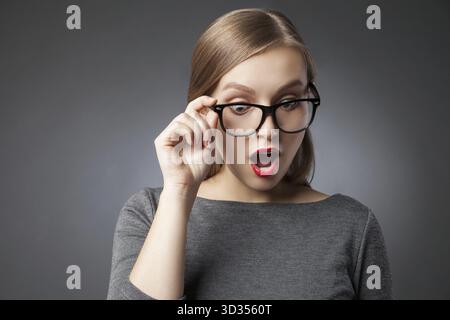 Amazed woman with red lips in glasses looking down with open mouth Stock Photo