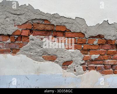 Exposed red brick wall with gray plaster background showing texture and urban decay concept. Mobile photo Stock Photo