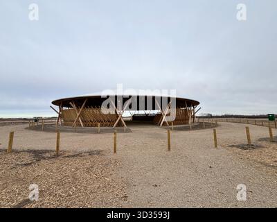 Timber amphitheatre with sweeping wooden roof and tiered seating on an indigenous reserve, set against vast prairies, symbolizing sustainable design. Stock Photo