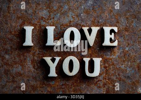 Inscription I love you spelled in wooden letters on an old rusty surface, close up, top view. The concept of happiness, love, romance and valentines d Stock Photo