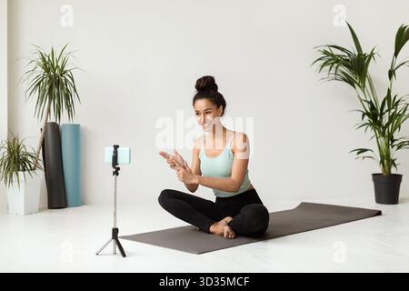 Smiling Female Yoga Instructor Records Video Tutorials in a Bright Studio Setting Stock Photo