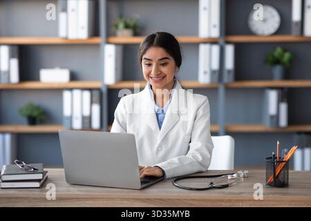 Young Indian Woman Doctor Working on Computer in Office During Pandemic Stock Photo