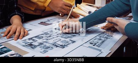 A dynamic scene of architects working together, showcasing hands engaged with blueprints and sketches on a wooden table filled with design tools and Stock Photo
