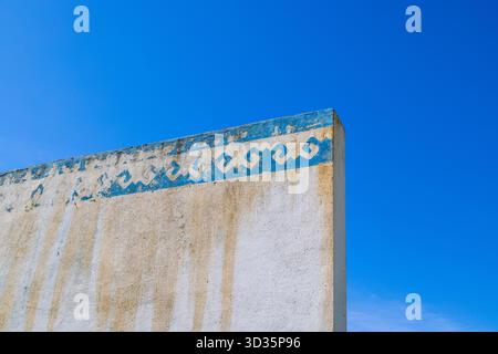 Weathered blue wall design outdoors under clear sky Stock Photo