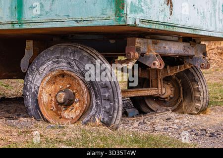 Rusty two-wheeled trailer in grassy outdoor setting Stock Photo