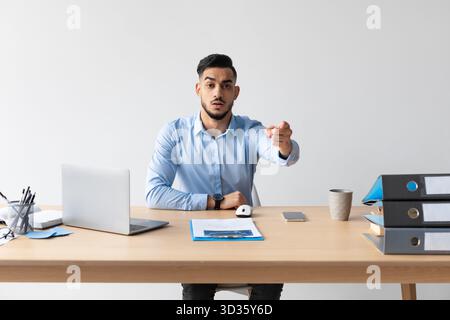 Focused Middle Eastern Businessman Pointing at Camera While Working at Desk With Laptop Stock Photo