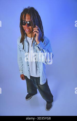 Young man with dreadlocks smiling and talking on phone Stock Photo