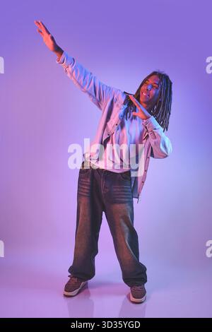 Stylish young man performing a dab gesture in purple neon light Stock Photo