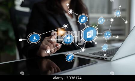 A business professional engages with a digital interface featuring networked icons on a laptop in a modern office setting, showcasing technology and Stock Photo