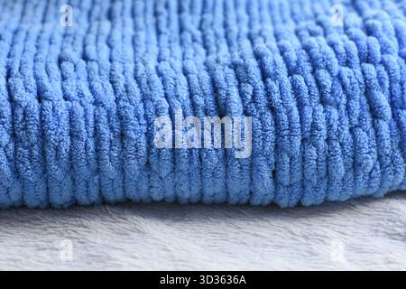Folded blue knitted blanket close-up on a gray surface Stock Photo