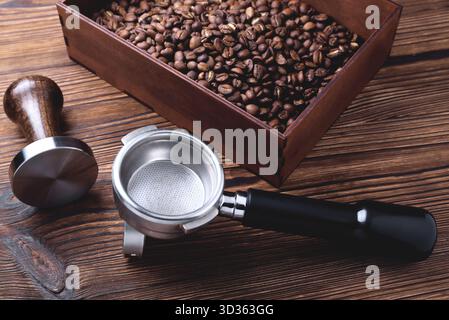a cup of coffee, coffee beans, a coffee horn and a tamper on a wooden background copy space, selective focus Stock Photo