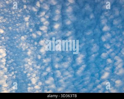 Clear blue sky with soft white clouds creating a peaceful and dreamy sky background Stock Photo