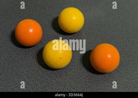 Scene21-Shot1-Close-up of four spherical objects in vibrant yellow and orange shades on a gray textured surface. Perfect for minimalist design, geomet Stock Photo