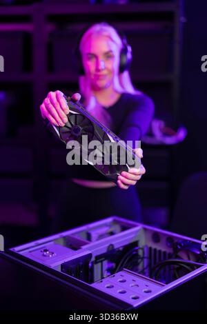 Female gamer in her twenties upgrades a gaming PC by installing a graphics card Stock Photo