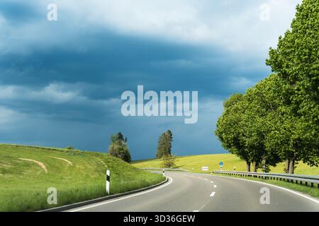 A curved road under a dramatic sky with incoming storm clouds. Stock Photo