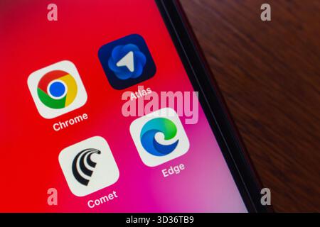 Smartphone displaying 4 popular browser app icons including Chrome, Edge, Comet, and Atlas, on an iPhone. AI-powered web browsing experience concept Stock Photo