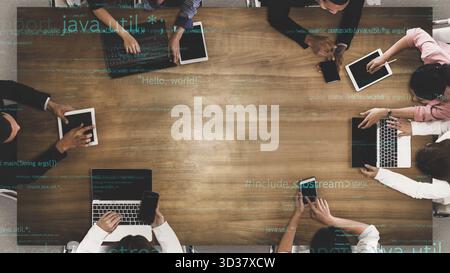 A modern office setting featuring a diverse team engaged in collaborative discussions, utilizing laptops and tablets for coding and innovative ideas Stock Photo