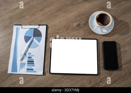 A flat lay workspace shows a tablet with a blank white screen beside a business report, a smartphone and a coffee cup, suitable for UX presentations a Stock Photo