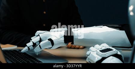 A close-up of a robotic arm interacting with a laptop in a modern workspace, highlighting the intersection of technology, automation, and human-like Stock Photo