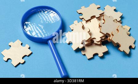 Finding the Missing Piece: Magnifying Glass Analyzing Jigsaw Puzzle Parts Stock Photo