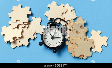 Time is Running Out: Alarm Clock Surrounded by Unassembled Jigsaw Puzzle Pieces Stock Photo