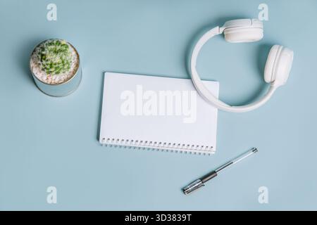 An empty notebook for recording with headphones and cacti on a blue background, top view, flat lay Stock Photo