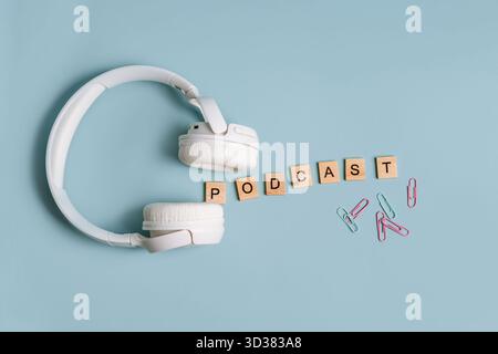 Top view on a blue background with wooden letters, the word podcast is laid out, flat lay with a notebook and headphones Stock Photo