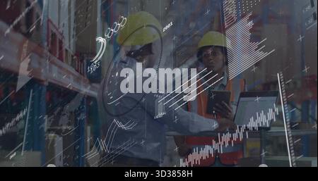Analyzing staff wearing safety gear interpreting data overlays on laptop and tablet in warehouse Stock Photo