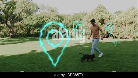 Playing man wearing mustard shirt bonding with black puppy in park, turquoise map pins, copy space Stock Photo