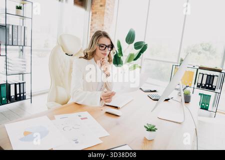 Confident young businesswoman analyzing financial reports in a bright modern office setting for strategic decision making Stock Photo