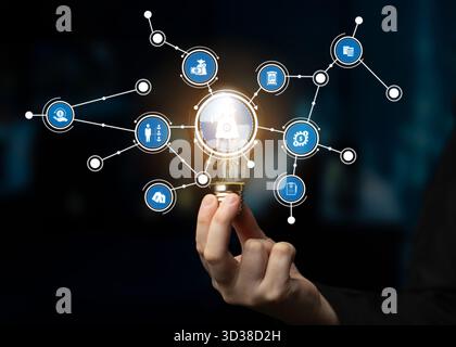 This image showcases a light bulb held in hand, surrounded by icons representing various ideas and technologies, signifying innovation, connectivity Stock Photo