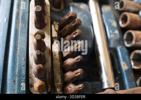 Close up of an old, rusty metal toolbox filled with vintage workshop equipment. collection of steel screwdriver bits and sockets showing years of wear Stock Photo