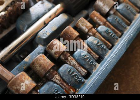 Close up of rusty old socket wrench set in dirty toolbox. weathered and forgotten hand tools show signs of age and neglect, creating gritty industrial Stock Photo