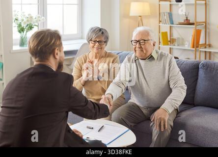 Older couple making deal, shaking hands with agent, financial advisor or medical insurance broker Stock Photo