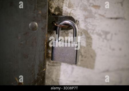 Closeup of silver padlock on rusty metal door showing security and durability concept. Stock Photo