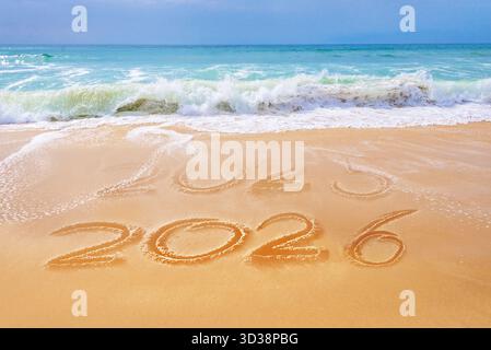 2026 written on the sand of a beach, ocean waves, travel new year holiday greeting card Stock Photo