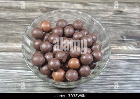bowl of chocolate-coated peanut, a confectionery made of a roasted peanut covered in a layer of chocolate, a popular snack with a crunchy, salty peanu Stock Photo