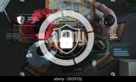 A diverse group of professionals engages in a brainstorming session about cybersecurity strategies, with a digital lock graphic symbolizing protection Stock Photo