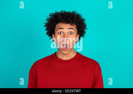 Surprised young man in red sweater against teal background captures astonishment for fashion lifestyle advertising Stock Photo